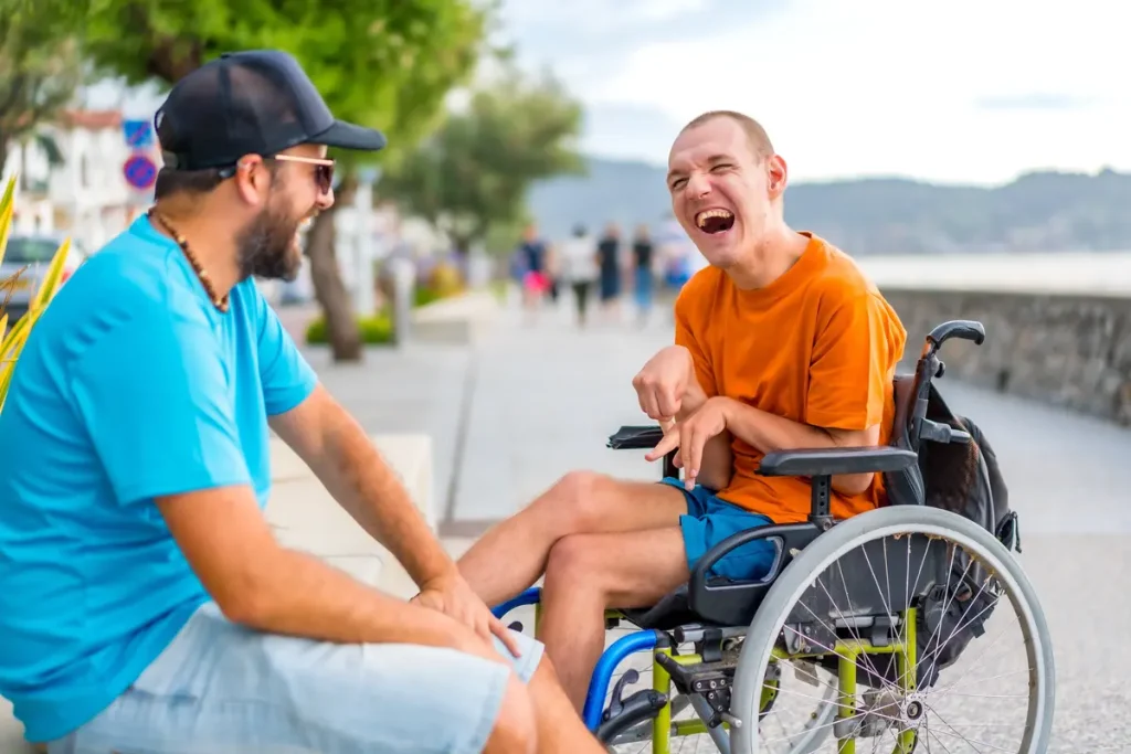 Disabled man in wheelchair laughing with support worker