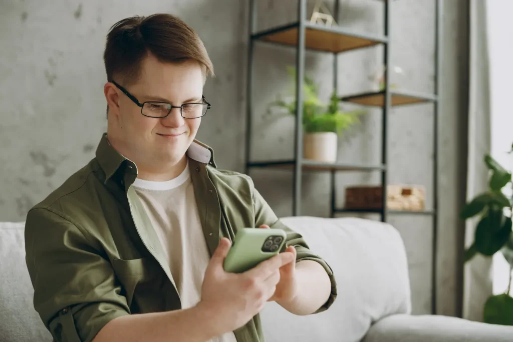 Disabled man with down syndrome using mobile phone