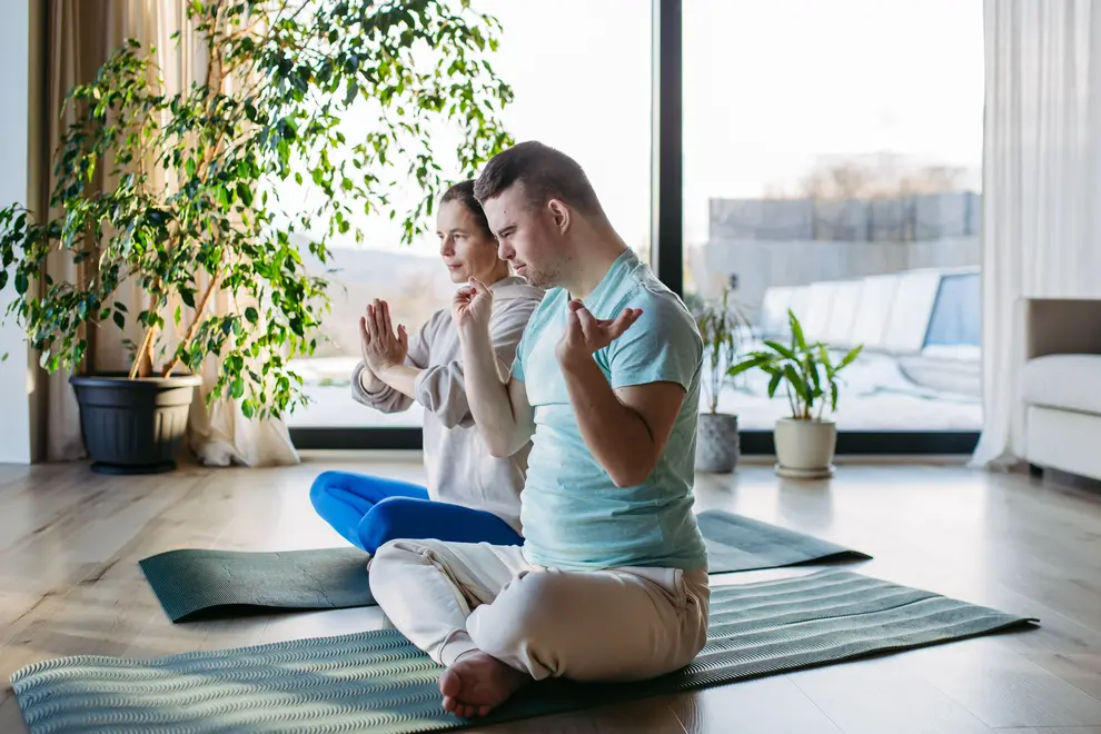 Disabled man with down syndrome doing yoga with support worker