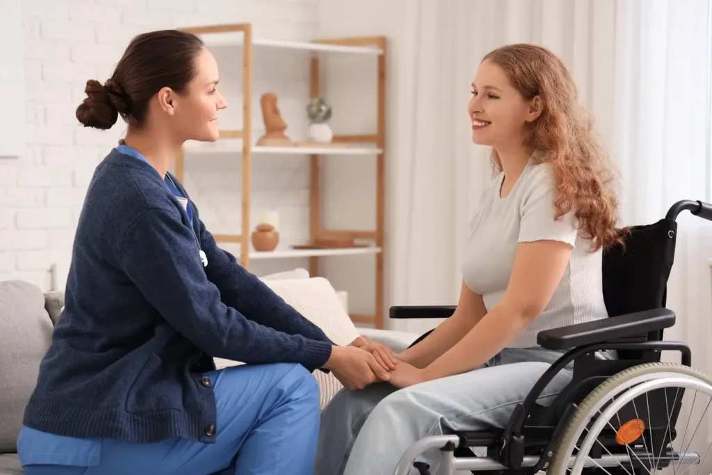 Nurse holding hands of disabled woman in wheelchair