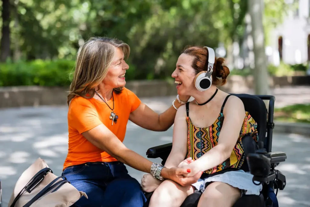 Disabled woman in wheelchair smiling with carer